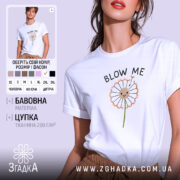 Футболка Кульбаба, біла, на моделі, з принтом у вигляді кульбаби з усміхненим обличчям, текстом 'BLOW ME' над принтом, фон ніжно-фіолетовий.