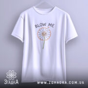 Футболка Кульбаба, біла, підвішена на вішалці, з принтом кульбаби та текстом 'BLOW ME', фон світло-сірий.