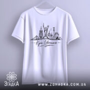 Футболка Київ Україна, біла, підвішена на вішалці, фон світло-сірий, принт з архітектурними пам'ятками Києва, напис 'Kyiv, Ukraine' під малюнком.