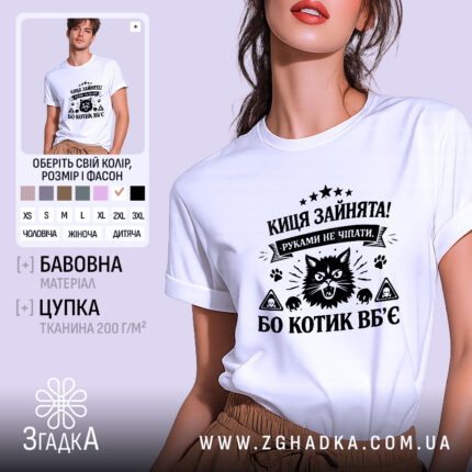 Футболка киця зайнята, біла, на моделі, з легким ракурсом спереду, фон світло-фіолетовий, принт чорного кольору з зображенням кота та текстом.