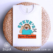 Футболка Лава Чікен, біла, складена на плоскій поверхні, фон світло-сірий, принт з персонажем, що махає рукою, текстом 'STEVE'S Tasty as hell!' та логотипом 'Lava Chicken', на плетеній основі.