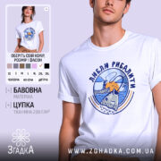 Футболка люблю рибалити, біла, зображена на молодому чоловікові, фон світло-фіолетовий, принт з рибою та рибалкою на фоні заходу сонця.