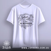 Футболка люблю себе, біла, підвішена на вішалці, фон світло-сірий, принт чорного кольору з написом 'Люблю себе, а тебе не впевнена' в декоративному стилі.