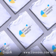 Футболка майбутньої пʼятикласниці білого кольору, зображена на моделі, яка позує з легким усмішкою. Фон ніжно-фіолетовий, а на футболці яскравий принт у вигляді жовто-блакитного соняшника та тексту "Тепер я п'ятікласниця – тримайтеся!".