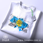 Футболка Мій Бердичів, біла, на плоскій поверхні, з видимим принтом, фон світло-сірий, принт з жовтими та блакитними кольорами, з написом 'Бердичів' та архітектурними елементами.