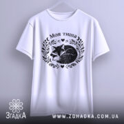 Футболка Моя тиша, біла, підвішена на вішалці, фон світло-фіолетовий, принт з зображенням сплячого лиса в обрамленні рослинних мотивів і сердець.