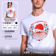 Футболка моє коріння тут, біла, зображена на моделі, фон світло-фіолетовий, принт з їжаком, червоними квітами та корінням, текст "Моє коріння тут" над принтом.