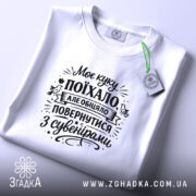 Футболка Моє куку поїхало, біла, на плоскій поверхні, фон світло-сірий, принт чорного кольору з текстом, на комірці є етикетка.