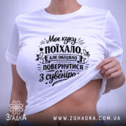 Футболка Моє куку поїхало, біла, на плоскій поверхні, фон світло-сірий, принт чорного кольору з текстом, на комірці є етикетка.