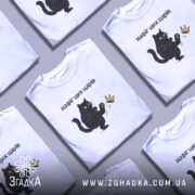 Футболка нафіґ цих царів, біла, на моделі, з принтом чорного кота, який піднімає лапу до корони, фон світло-фіолетовий, деталі принта яскраві, текст чорний.