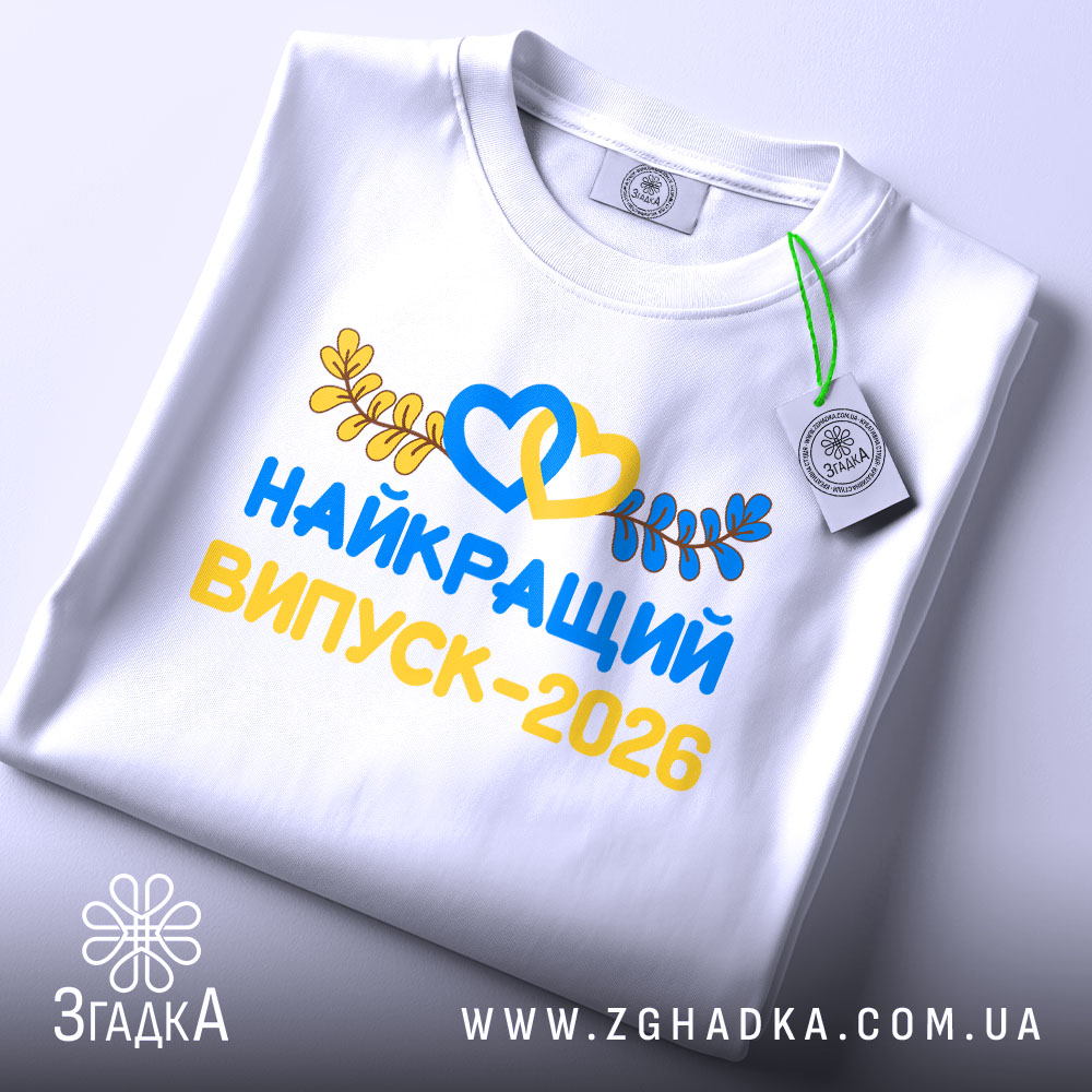 Футболка найкращий випускний 2026, біла, на столі, з видимим етикеткою, фон світло-сірий, принт яскравий, з сердечками та листям, напис великими літерами.