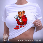 Футболка не роби мені нєрви. Біла футболка, зображена зверху, ведмідь в червоному капюшоні з сокирою, текст "НЕ РОБИ МЕНІ НЕРВИ!" під малюнком, на фоні світло-сірого кольору, з етикеткою на комірці.