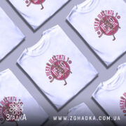 Футболка нехай щастить білого кольору, зображена на молодому чоловікові, який позує на світлому фоні. Принт на футболці містить малюнок скелета, що біжить, з написом 'Нехай щастить' у червоному кольорі, оточеним зірками.