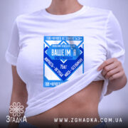 Футболка нічого не злипнеться, біла, зображена зверху, на плоскій поверхні, фон світлий, принт у синіх відтінках з текстом і графічними елементами, на ярлику зелена стрічка.