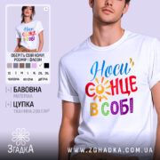 Футболка носи сонце в собі, біла, зображена на молодій людині, ракурс з близька, фон пастельного кольору, принт з написом 'Носи сонце в собі' у яскравих кольорах: червоний, жовтий, синій, зелений та фіолетовий, з елементами сонця.