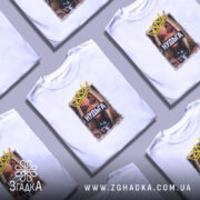 Футболка Нудьга корона, біла, на моделі, ракурс спереду, фон світло-фіолетовий, принт з зображенням жінки з короною та написом 'Нудьга' на чорному фоні.