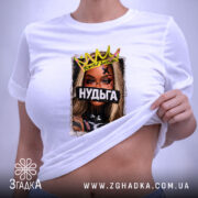 Футболка Нудьга корона, біла, на столі, ракурс зверху, фон світло-сірий, принт з зображенням жінки з короною та написом 'Нудьга' на чорному фоні, з біркою.