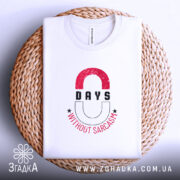 Футболка Нуль днів без сарказму, біла, складена на кошику, фон світло-сірий, принт з червоними і чорними літерами, напис '0 DAYS WITHOUT SARCASM' з зірочками.