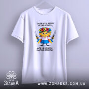 Футболка образити може кожен. Біла футболка, зображена з легким нахилом, фон світло-фіолетовий. Принт з ілюстрацією дівчинки в українському вбранні, тримає ножі, текст чорного кольору розташований зверху і знизу.