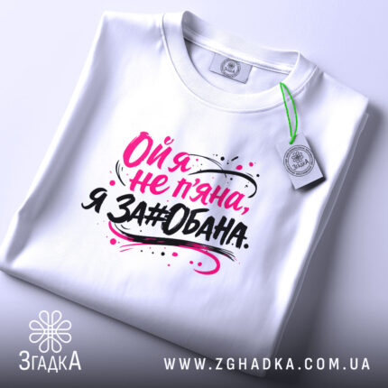Футболка ой я не пʼяна, на фото зображена складена біла футболка, принт на ній яскравий, текст виконаний у чорному та рожевому кольорах, фон світло-сірий, на футболці є етикетка.
