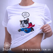 Футболка Пес супергерой, біла, на столі, фон світло-сірий, принт з зображенням собаки в синьому костюмі та червоному плащі, текст "NO WORRY" над собакою і "I am saving you Human" під ним, з етикеткою на рукаві.