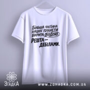 Футболка планета вкрита водою, біла футболка на вішалці, ракурс спереду, фон світло-сірий, принт чорного кольору з текстом: 'Більша частина нашої планети вкрита водою. Решта – дебілами.'