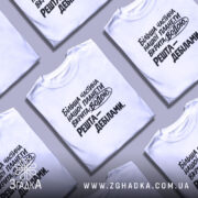 Футболка планета вкрита водою, біла футболка на моделі, ракурс з близька, фон світло-фіолетовий, принт чорного кольору з текстом: 'Більша частина нашої планети вкрита водою. Решта – дебілами.'