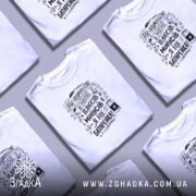 Футболка плюси мінуси: біла футболка на молодому чоловікові, зображена в анфас, фон світло-фіолетовий, принт чорного кольору з текстом і графічними елементами.