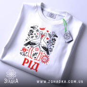 Футболка рід білого кольору, зображена на плоскій поверхні, з акцентом на принт, що містить двох лелек, оточених рослинними елементами. Напис 'РІД' виконаний червоним кольором. На футболці видно етикетку з логотипом бренду.