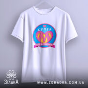 Футболка супер мама, біла, підвішена на вішалці, фон світло-сірий, принт з написом 'СУПЕР' та серцем, кольори принта: рожевий, жовтий, блакитний.