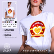 Футболка супермама білого кольору, зображена на моделі, яка позує з легким усмішкою. Принт на футболці яскравий, з червоним та жовтим кольорами, містить текст 'СУПЕРМАМА 24/7' у серці. Фон м'який, пастельний, що підкреслює стиль футболки.