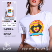 Футболка супермама, біла, на моделі, ракурс спереду, фон світло-фіолетовий, принт з жовтим колом, чорними крилами та сердечками, напис 'СУПЕРМАМА' у верхній частині.