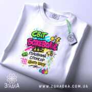 Футболка світ божеволіє, біла, на плоскій поверхні, з принтом в центрі, фон світло-сірий, принт яскравий з текстом і графічними елементами в кольорах: рожевий, зелений, жовтий, чорний, з малюнками грошових купюр, динамічними лініями та вогнем.