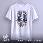 Футболка своє українське, біла, підвішена на вішалці, з принтом у вигляді двох дівчат у національному вбранні, фон світло-сірий.