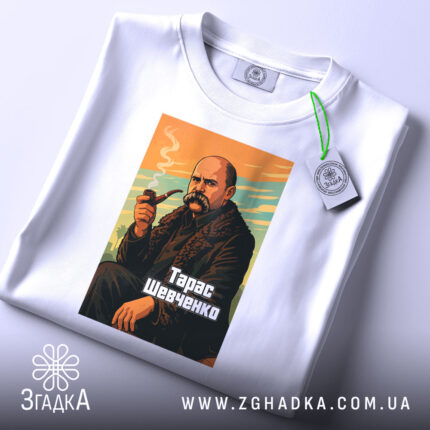 Футболка Тарас Шевченко, біла, на столі, з ракурсу зверху, фон світло-сірий, принт з зображенням Тараса Шевченка з сигаретою, кольори принта: оранжевий, зелений, чорний, текст "Тарас Шевченко" внизу, на футболці є етикетка.