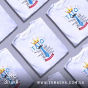 Футболка тато завжди правий, біла, на моделі, з легким усмішкою, фон світлий, принт з написом 'ТАТО' у блакитному кольорі, корона жовта, деталі тексту навколо.