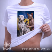 Футболка тату кіт, біла, на столі, з принтом, на якому зображені далматинець і сфінкс на фоні українського прапора, етикетка з зеленим шнурком, деталі принта яскраві.