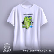 Футболка Травозавр білого кольору, підвішена на вішалці. Принт зображає зеленого динозавра в окулярах, що тримає колбу з блакитною рідиною та пакет з травою. Фон світло-сірий, а текст 'ТРАВОЗАВР' розташований над принтом.