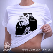 Футболка ти мій я твоя, біла футболка на плоскій поверхні, ракурс зверху, фон світлий, принт з чорними елементами, що зображує пару, текст на футболці: 'Ти мій... Я твоя... Ми разом - книга про життя...', з етикеткою зеленого кольору.