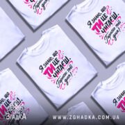 Футболка ти це читаєш, біла, з ракурсу спереду, на моделі з коротким рукавом, фон світло-фіолетовий, принт з текстом чорного та рожевого кольорів, оформлений у веселому стилі.