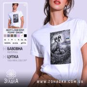 Футболка українські лелеки сімейний символ, біла, на моделі з легким макіяжем, фон світло-фіолетовий, принт з двома лелеками та пташенятами в гнізді, на задньому плані український прапор.