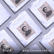 Футболка Василь Стус, біла, зображена на молодому чоловікові, ракурс з близької відстані, фон світло-фіолетовий, принт з портретом Василя Стуса в стилі поштової марки з написом 'STUS 01' та 'NE SKORENYI'.