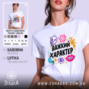 Футболка Важкий характер, біла, зображена на моделі, яка позує з легким усмішкою, фон пастельного кольору, принт складається з кольорових елементів, таких як череп, квіти, очі та зірки, текст "Важкий характер" великими чорними літерами.