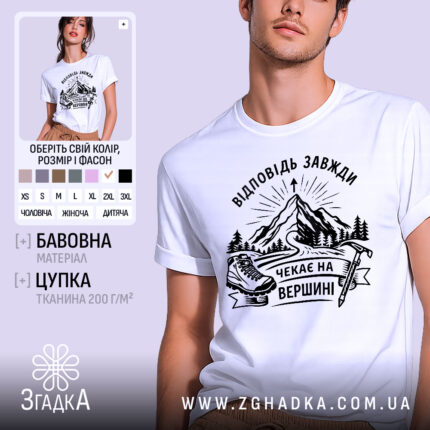 Футболка відповідь завжди чекає. Біла футболка на чоловікові, зображена в анфас, фон світло-фіолетовий. Принт з чорними елементами, що зображає гори, лижі та напис 'Чекає на вершині'.