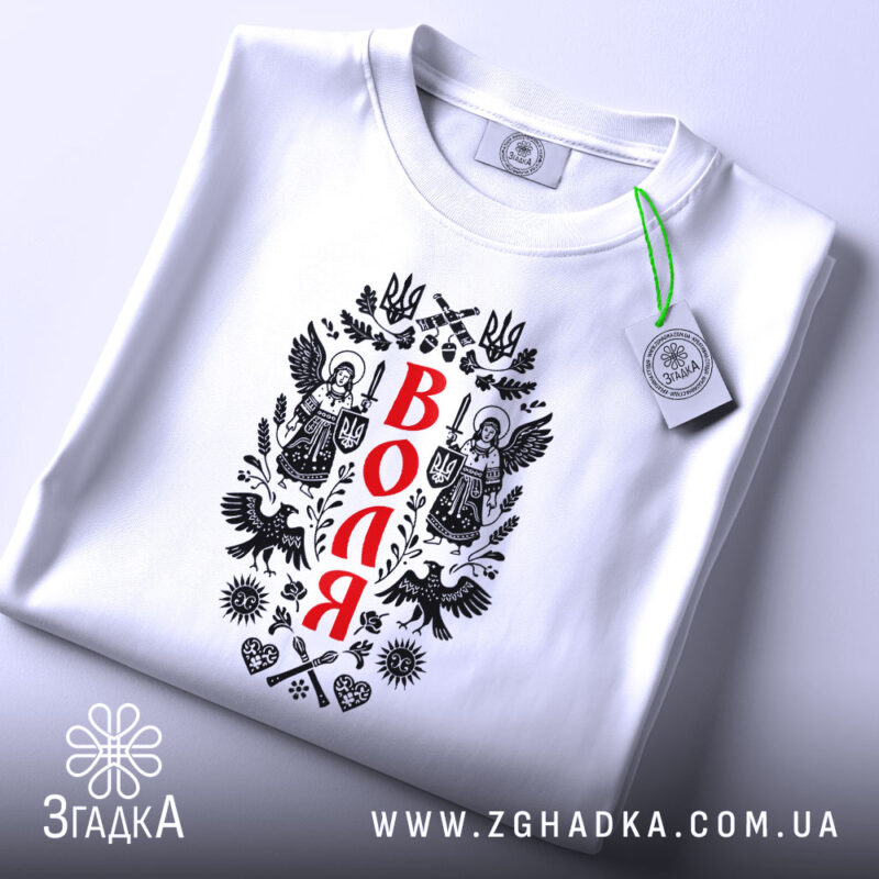 Футболка воля, складена на поверхні, білого кольору, з принтом на передній частині, зображення ангелів та герба України, фон світло-сірий, на футболці є етикетка з зеленим шнурком.