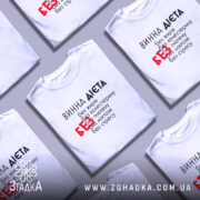 Футболка винна дієта, біла, на моделі, з текстом на грудях, фон світло-сірий, принт чорний з червоним акцентом на слові 'БЕЗ'.