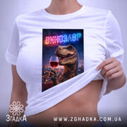 Футболка винозавр, біла, на плоскій поверхні, ракурс зверху, фон світлий, принт з динозавром, що тримає келих червоного вина, з неоновим написом 'ВИНОЗАВР', на етикетці зелена стрічка.