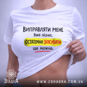 Футболка виправляти мене вже пізно, біла футболка, зображена зверху, фон світло-сірий, принт чорного, жовтого та червоного кольорів з текстом на українській мові, з етикеткою на комірці.