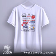 Футболка випускник білого кольору, підвішена на вішалці. Принт на футболці містить текст 'ВИПУСКНИК' та інші елементи, виконані в червоному, чорному та синьому кольорах. Фон світло-сірий, що підкреслює простоту дизайну.