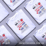 Футболка випускник білого кольору, зображена на молодій людині, яка позує з легким усмішкою. Принт на футболці містить текст 'ВИПУСКНИК' та інші елементи, виконані в червоному, чорному та синьому кольорах. Фон світло-фіолетовий, що підкреслює яскравість дизайну.